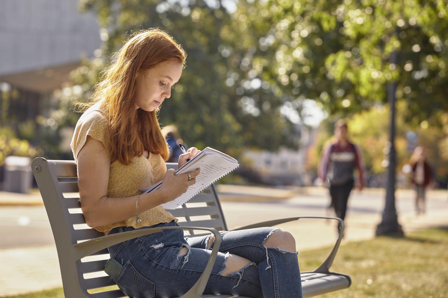 一位<a href='http://awic.ngskmc-eis.net'>全球十大赌钱排行app</a>学院的学生在校园里的长椅上读书.